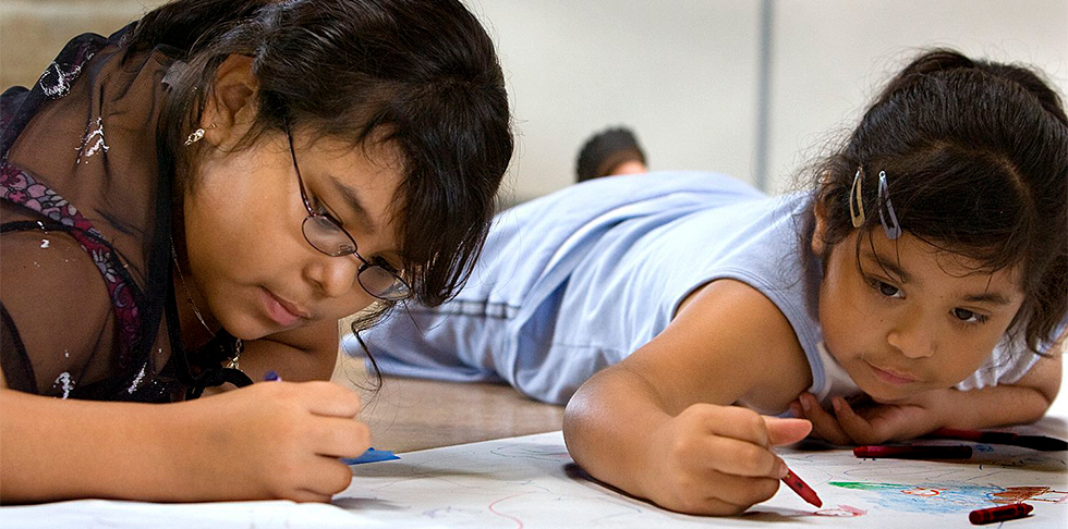 Pictured:  Two children lay on the floor, coloring